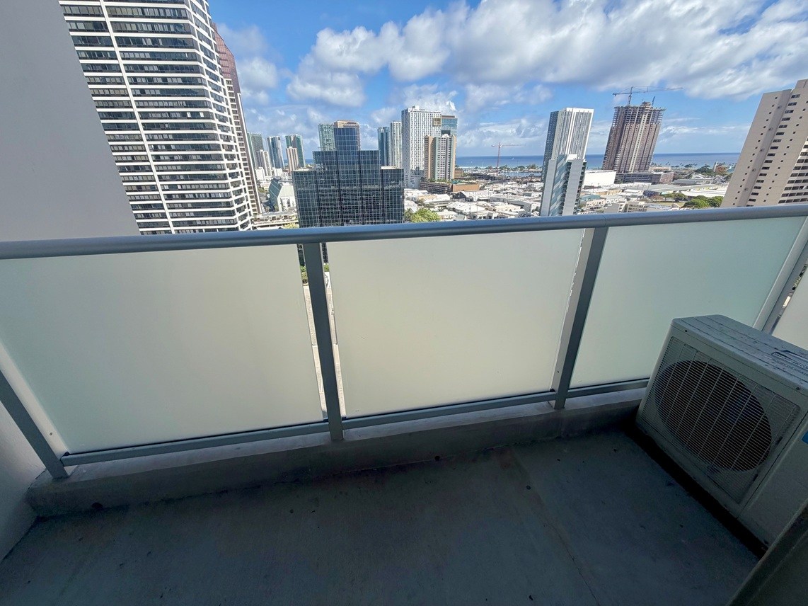 A balcony with a window overlooking a cityscape.